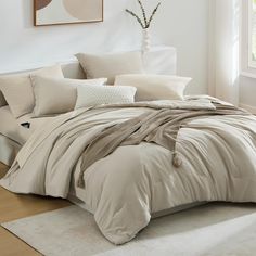 a bed with white sheets and pillows on top of it in a room next to a window