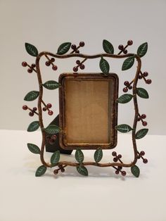 an old fashioned photo frame with leaves and berries on the front, sitting on a white surface