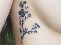 a close up of a flower tattoo on the side of a woman's stomach