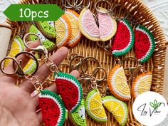 a person is holding some fruit shaped key chains in front of a wicker basket