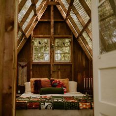 a bed in a room with wooden walls and beams on the ceiling is made from wood planks