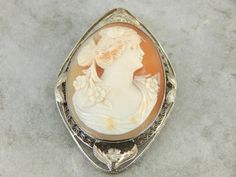 This cameo is stunning! Crafted of 14K white gold, the ornate bezel with filigree wire and floral decoration provides a lovely framework for this classic cameo. The image here is immaculately carved, and the large size allows for fine detail. Cameo is the art of carving a layered material, creating a portrait or landscape with the difference in the colors. While traditionally done in shell, banded onyx has been used in cameo work - particularly in Greece and Italy - for hundreds, if not thousand Two Face, Cameo Jewelry, Antique Pendant, Vintage Cameo, Carved Shell, Gold Diamond Necklace, Cameo Brooch, Cameo Pendant, Gold Brooches