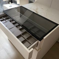 an open drawer in the middle of a kitchen counter with drawers on each side and shelves below