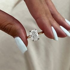 a woman's hand with white nails and a ring on her finger holding a diamond