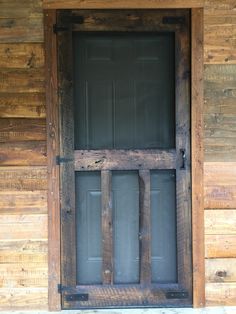 an open wooden door on the side of a wood building with metal bars in it