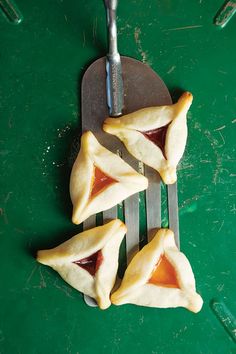 four small pastries on a green surface with a fork and knife next to them