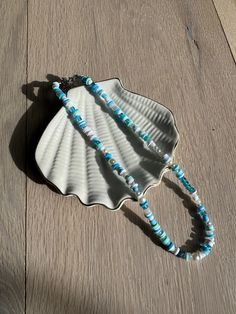 a shell shaped necklace with blue beads on it