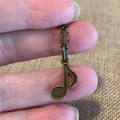 a person is holding a tiny musical note keychain in their left hand,