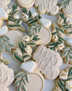 some decorated cookies are laying on a table with white flowers and leaves in the middle