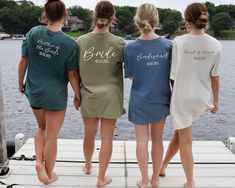 three women standing on a dock with their back to the camera, wearing matching shirts that say bridesmaids