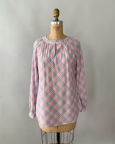 "An adorable spring blouse by Levi's from the late 1970s - early 1980s. Made from a pastel plaid cotton blend in shades of pale pink, blue and green, the blouse has a gathered neckline with a front button closure and keyhole, and long, puffy bishop sleeves that can also be rolled/cuffed and buttoned in place with the attached tab. Looks so cute tucked into high waisted jeans! Measurements Tag: Levi Strauss Material: 55% Cotton 45% Polyester Size: tagged a vintage size 10 and fits a modern small Plaid Long Sleeve Top For Spring, Spring Long Sleeve Plaid Top, Preppy Pink Tops For Fall, Relaxed Fit Plaid Blouse For Daywear, Pastel Long Sleeve Tops For Spring, Spring Plaid Relaxed Fit Tops, Plaid Relaxed Fit Tops For Spring, Spring Long Sleeve Preppy Tops, Preppy Long Sleeve Spring Tops