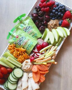 an assortment of fruits, vegetables and crackers arranged on a platter for a snack