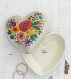 two heart shaped dishes sitting on top of a white table next to a wedding ring