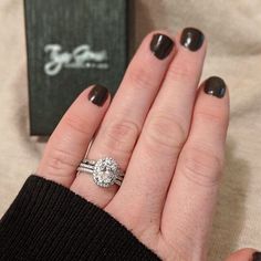 a woman's hand with a ring on it and a box in the background