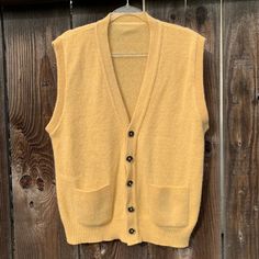 This is a beautiful wool/wool blend vest from the 1960s The original tag is no longer there  It fits like a men's extra large, but please see measurements for the exact fit I absolutely adore this vest and it gives me Mister Rodgers vibes 🥰 It buttons up the front for closure and has two front pockets for your goodies I have not noticed any flaws! I love this color, it's such a happy color imo, it's like a golden yellow, a mellow yellow lets say. The first 4 pics depict the actual color better then the rest of the photos just fyi  measurements as follows: pit to pit lying flat is 24" inches  length is 27" inches  I ship priority mail with tracking! Thanks for looking :) Retro Sleeveless Fall Outerwear, Retro Sleeveless Outerwear For Fall, Retro Fall Vest With Pockets, Vintage Sleeveless Winter Vest, Vintage Wool Sweater Vest For Winter, Vintage Wool Sleeveless Sweater Vest, Vintage Sleeveless Wool Sweater Vest, Retro Sleeveless Sweater Vest For Fall, Retro Wool Sleeveless Vest