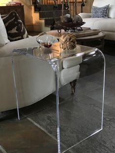 a cat sitting on top of a glass table in a living room next to a couch