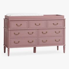 a pink dresser with gold handles and drawers