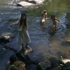 some people are standing in the water near rocks