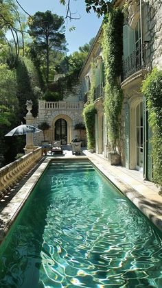 an outdoor swimming pool surrounded by greenery and stone buildings with balconies on either side