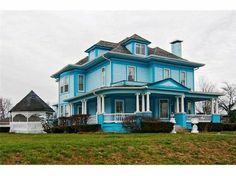 a large blue house sitting on top of a lush green field