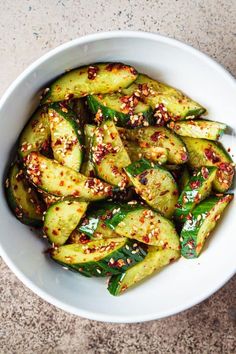 a white bowl filled with cooked zucchini on top of a marble countertop