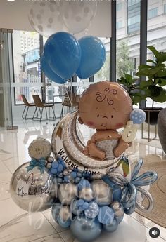 a baby is sitting on the moon surrounded by blue and white balloons in an office lobby