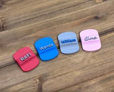 four small personalized coasters sitting on top of a wooden table