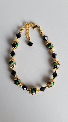 This bracelet is made of round black Cloisonné' beads, Swarovski Jet Black Crystal and gold plated beads and findings. It has a 1" extension with a beaded drop making it adjustable. It has a lobster claw clasp.  Cloisonné is the technique of creating designs on metal vessels (cloisons) with colored-glass paste placed within enclosures made of copper or bronze wires, which have been bent or hammered into the desired pattern.  Custom Orders are always welcome! Ask about free sizing. Making Jewelry For Beginners, Swarovski Crystal Jewelry, Black Flower, Beads Bracelet, Black Crystals, Making Jewelry, Jet Black, Jewelry Ideas, Crystal Jewelry