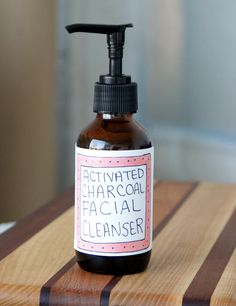 a bottle of activated charcoal facial cleanser sitting on top of a wooden countertop