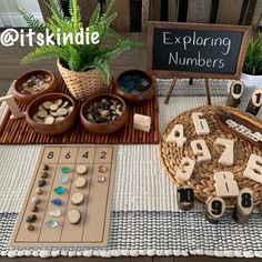 a table topped with lots of wooden letters and numbers next to pots filled with plants