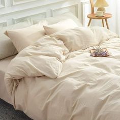 a bed with white sheets and pillows in a room next to a lamp on a table