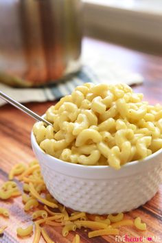 a white bowl filled with macaroni and cheese on top of a wooden table