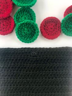 there are crocheted balls on the table next to each other and one is red, green and black