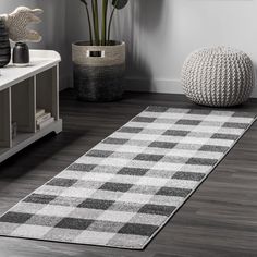 a white and black rug in a living room next to a potted plant on the floor