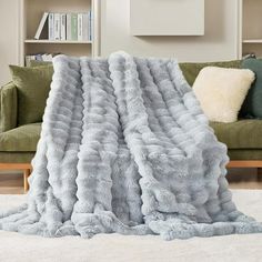 a large fluffy blanket sitting on top of a white rug next to a green couch