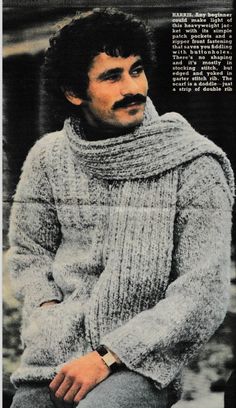 a man with a moustache is wearing a knitted sweater and turtle neck