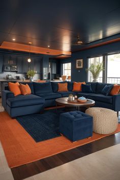 a living room filled with blue couches and orange pillows on top of a rug