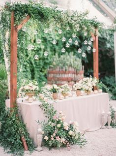 a table with flowers and greenery on it for an outdoor wedding reception in the garden