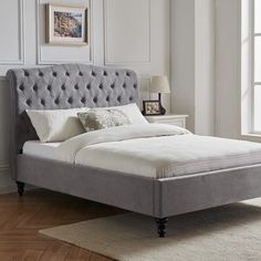 a bed that is in a room with white walls and wooden floors, along with a rug on the floor