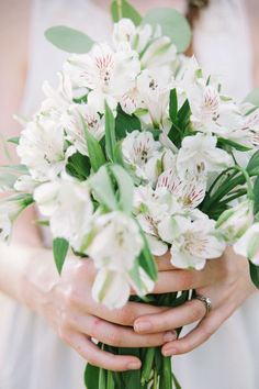 a woman holding a bouquet of white flowers