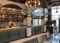 an empty restaurant with tables and chairs in front of the counter, lights hanging from the ceiling