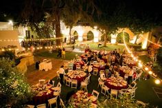 an outdoor event with many tables and chairs set up for formal function, surrounded by greenery