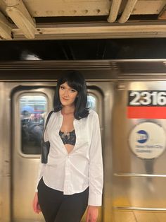 a woman standing in front of a subway train door with her hand on her hip