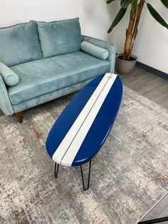 a blue and white surfboard sitting on top of a rug next to a couch