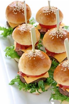 mini hamburgers with cheese and lettuce are arranged on a white platter