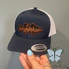 Join the retro trucker hat trend with our Bass Fish Mountain Leather Patch Adult Unisex Cap! Made with high-quality materials, this cap features a leather patch showcasing a bass fish and mountains. Perfect for outdoor enthusiasts, this hat adds a stylish touch to any outfit while protecting you from the sun. The leather patch designs are affixed with adhesive for very secure attachment to the hat. Due to monitor colors, patches and hat colors may be slightly different in person. Custom leather patch hats are made from laser-engraved LEATHERETTE material.  Availiable in YP Classics and Richardson 112! Trucker Snapback Hat For Fishing, Trucker Baseball Cap With Curved Bill For Fishing, Trucker Baseball Cap For Fishing With Curved Bill, Fishing Trucker Cap With Curved Bill, Trucker Hat With Leather Patch For Outdoor Activities, Brown Snapback Trucker Hat For Fishing, Trucker Snapback Hat With Curved Bill For Fishing, Leather Snapback Trucker Hat For Outdoor Activities, Rhinestone Hoodie