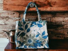 a blue and white bag sitting on top of a wooden table next to a pot