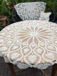 a white doily sitting on top of a wooden table next to potted plants