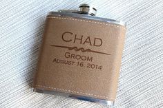 a flask with the name chad groom on it is sitting on a white blanket