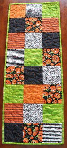 an orange and black patchwork quilt on a wooden table